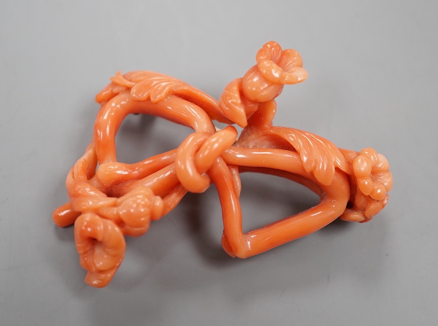 A yellow metal mounted coral 'floral knot' brooch, 56mm.
